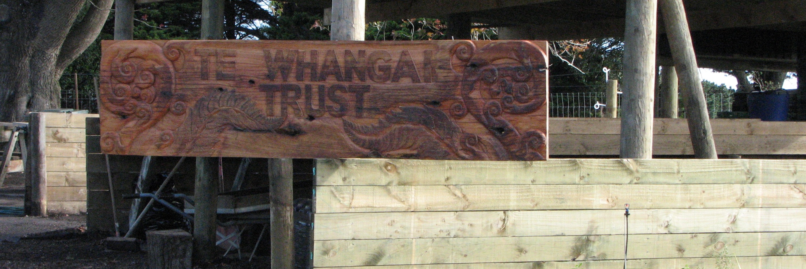 Te Whangai Trust signage carved from a slab of macracarpa by trainees' Whanau An image of Te Whangai Trust signage carved from a slab of macracarpa by trainees' Whanau.